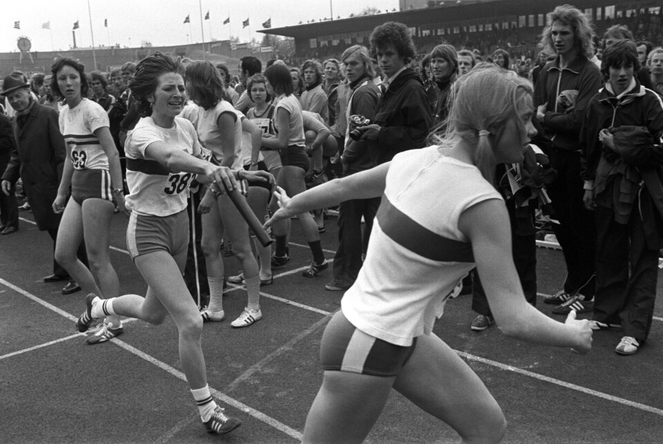 Marianne Skorgan veksler med ankerkvinne for Tyrving, Bente Jacobsen, 11. mai 1975. En kvinne rekker en annen kvinne stafettpinnen på Bislett stadion.