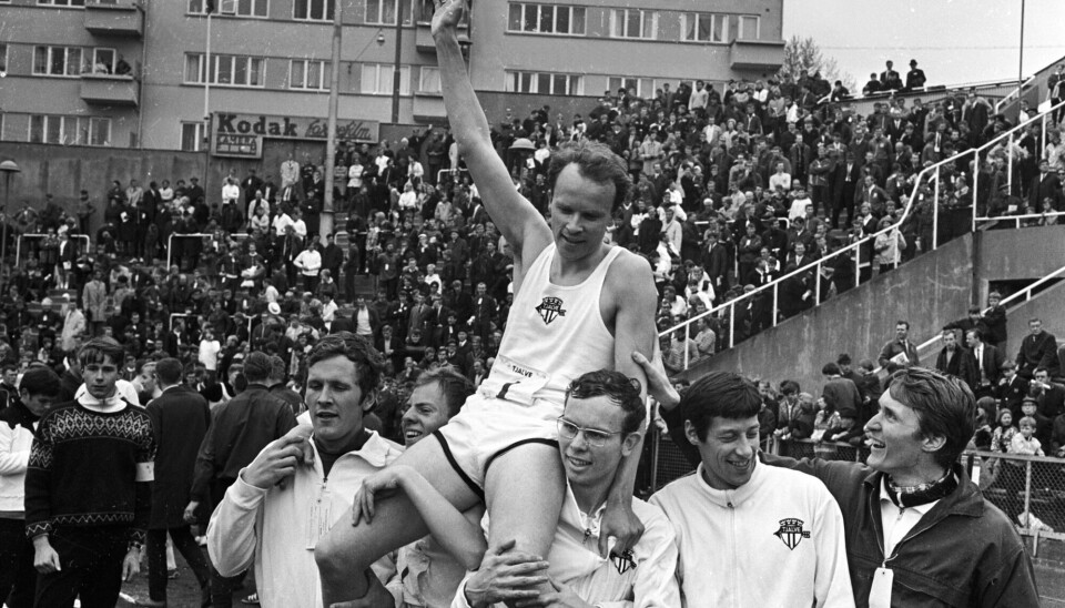 Tjalve feirer seieren i eliteklassen for menn under Holmenkollstafetten i 1969. Fem glade løpere holder opp en sjettemann som strekker hånda i være. I bakgrunnen sees en fullsatt tribune på Bislett stadion.