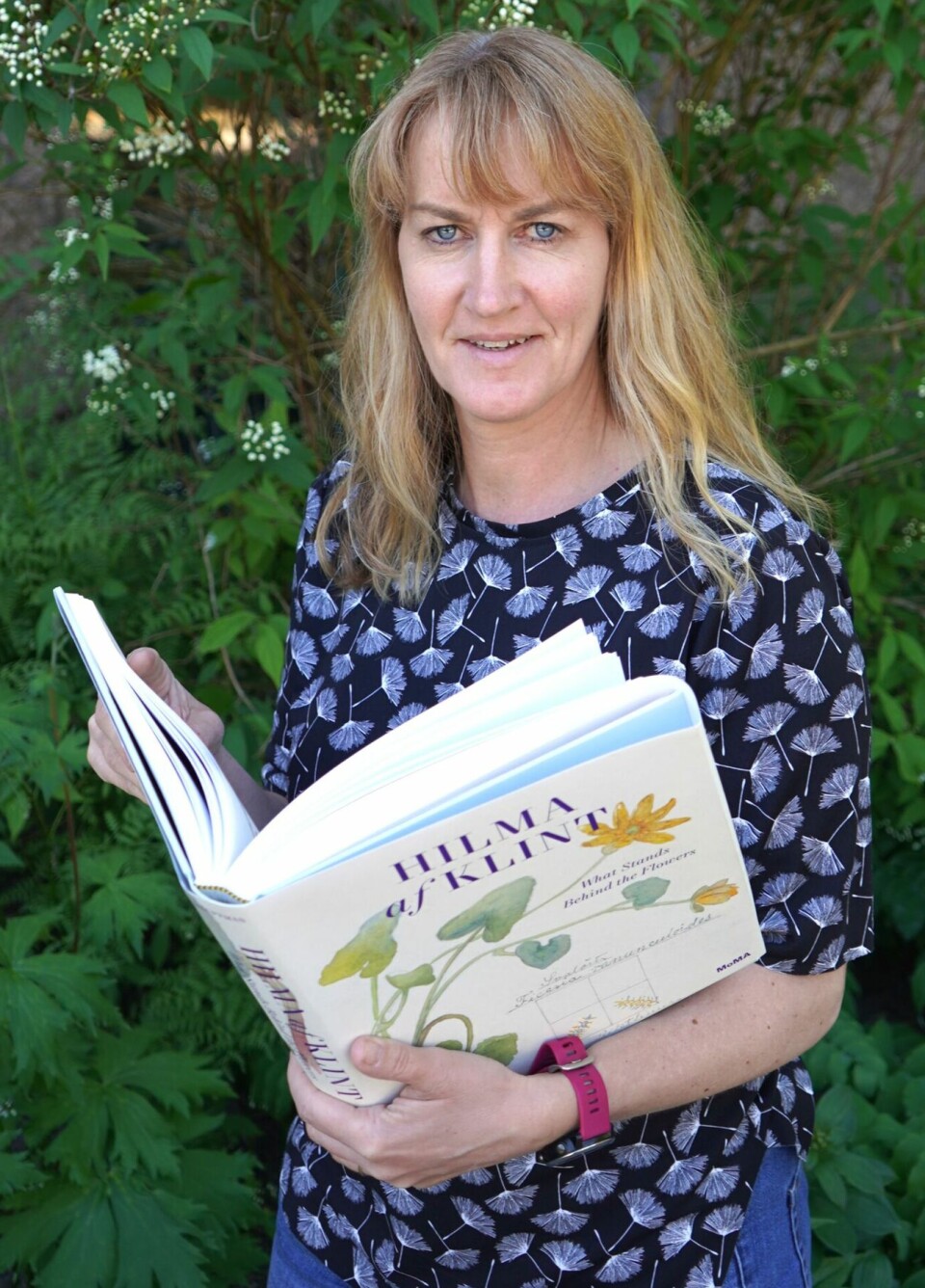 Charlotte Sletten Bjorå blar i boken What stands behind the flower.