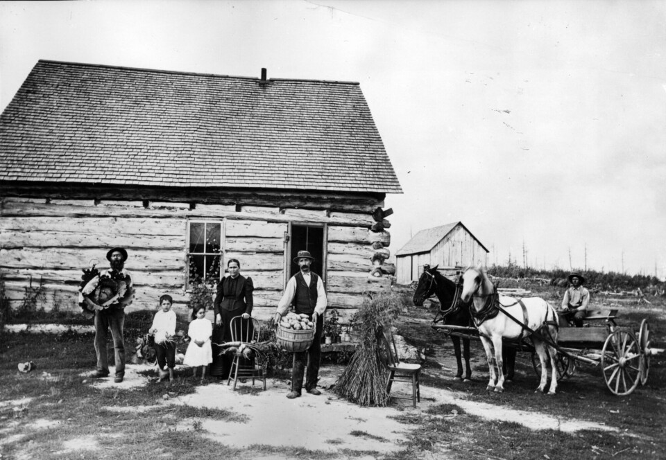 Innvandrere fikk kjøpe mye land for en rimelig pris etter at dakota-folket ble fordrevet. Bildet er tatt i Minnesota noen år etter dakota-krigen. Nybyggere i USA foran hus. Historisk bilde.