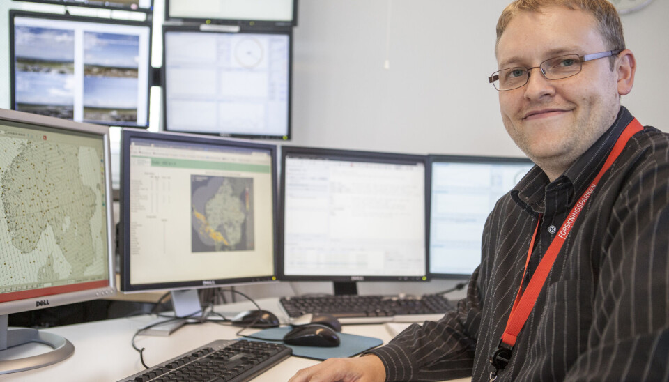 Statsmeteorolog Håkon Mjelstad ved Meteorologisk institutt tror Nesbyen beholder varmerekorden for denne gang. Blid mann med kort, brunt hår og briller sitter ved en pult med fire skjermer. På veggen bak ham henger ytterligere fire skjermer.