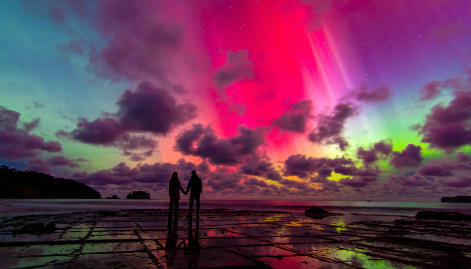 Et par holder hender under en eksplosjon av sørlys, også kalt Aurora Australis.