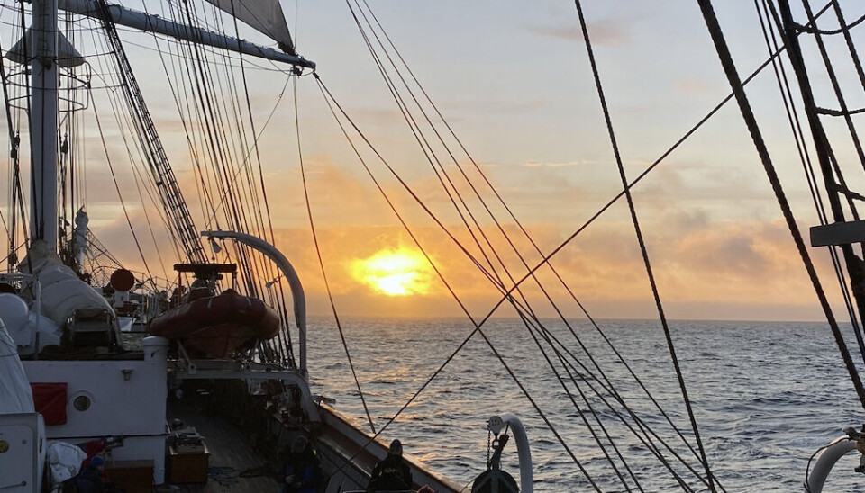 Seiling i soloppgang. Sol og seilskip med folk på dekk
