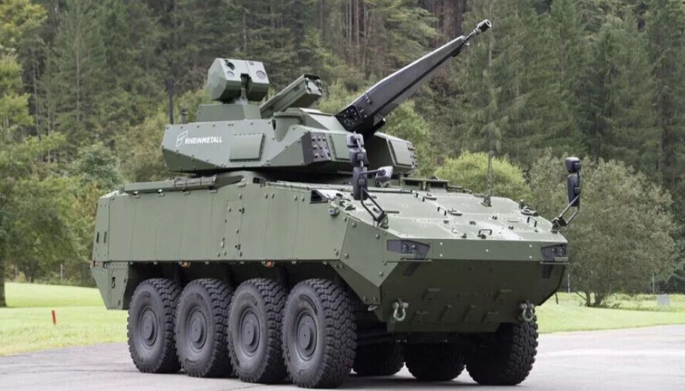 Det tyske selskapet Rheinmetalls Skyranger 30 er den danske hærens nye luftvern. Tårnets 30-millimeter maskinkanon fra Rheinmetall bekjemper fly, helikoptre og droner, sammen med et missilsystem. Her er det montert på en kampvogn. Et grønt, åttehjuls, pansret militærkjøretøy med tårn og kanon står på en asfaltert plass med trær og grønne områder i bakgrunnen.