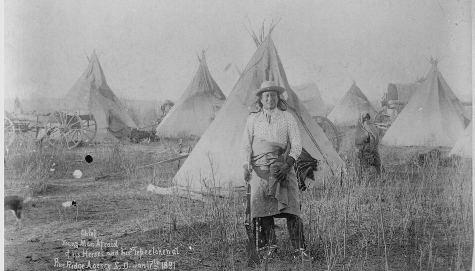 En mann av Oglala-Lakota-folket på Pine Ridge-reservatet i Sør-Dakota i 1891. Mann foran tipier.
