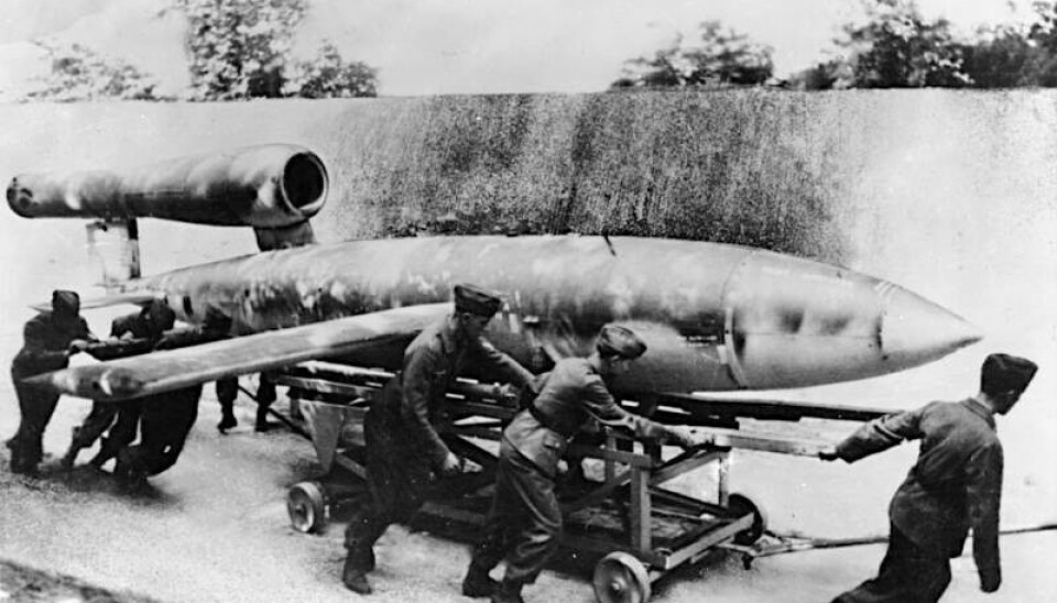 Tyske soldater trekker en V1-bombe til mot utskytningsrampen. Sort-hvitt-bilde viser soldater som trekker en vogn med en diger bombe som ligner et fly uten cockpit.