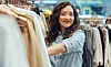 Glad kvinne ser på klær i butikk.