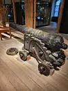 Eldre skipskanon på treunderstell utstilt på tregulv i museum.