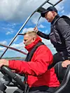 To menn med redningsvester styrer en motorbåt.