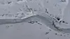 Luftfoto av delvis islagt smeltevannselv som slynger seg gjennom snødekt landskap.