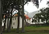 Utstein kloster med hvite murbygninger bak en rekke trær og gressplen