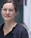 Vigdis Vandvik står innendørs i en lys korridor og ser mot kamera