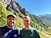 De to forskerne i sola ute i naturen med grønne fjellsider bak seg.