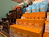 Butikkhylle fylt med solkrembokser og flasker i blå, oransje og mørke emballasjer.