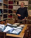 Professor Svein Harald Gullbekk står foran et bord med masse poser som inneholder mynter fra Mørstad-skatten, omringet av bokhyller fulle av bøker.
