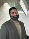 Aman Shahal står innendørs foran et lyst vindu.