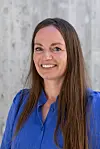 Portrett av Melanie Stecher foran en lys vegg, iført blå skjorte.
