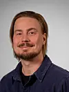 Portrett av Erlend Grenager Sørmo foran grå bakgrunn.