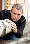 Erik Larnøy holder og undersøker en trestamme.