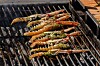 Sjøkreps med grønn marinade ligger på en grillrist over varm kullgrill.