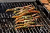Sjøkreps med grønn marinade ligger på en grillrist over varm kullgrill.