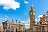 Big Ben og Westminster-bygninger i London under blå himmel.