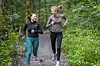 To kvinner løper på en skogssti omgitt av grønn skog i Oslo.