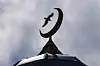 Halvmånesymbol på taket av Islamic Cultural Centre i Oslo mot grå himmel.