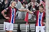 Erling Braut Haaland og Martin Ødegaard smiler og tar hverandre i hånda på stadion under kamp mot Italia. Det regner. Publikum skimtes i bakgrunnen med regnkåper på.
