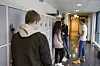 Elever står ved bokskap i en skolekorridor, mens en gutt står alene i forgrunnen.