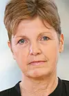 Nærbilde av en kvinne med kort hår foran en lys bakgrunn.