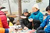 Barn står samlet rundt et bord ute i skogen og lager mat ved en liten leirplass.