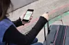 Kvinne med koffert ser på mobilskjerm med kart.