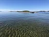 En svært liten øy med sandstrand sett fra havet.