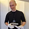 Sigurd Stenwig holder en pistol med hvite hansker i et lyst rom.