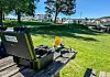 En drone og et svart utstyrsetui står på en benk i en park med vann og båter i bakgrunnen.