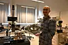 En mann står i et laboratorium og holder en metallring med elektroniske komponenter.