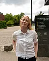 En kvinne står utendørs foran et skilt ved Universitetet i Oslo.