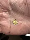 Nærbilde av en liten gullfarget metallbit i en åpen hånd.
