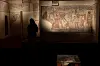 Besøkende foran opplyste veggmalerier i et mørkt galleri ved National Etruscan Museum of Villa Giulia.