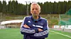 En mann i treningsjakke står med armene i kors på en fotballbane.