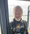 Stein Mortensen står i en døråpning med vann og landskap bak seg.