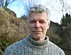 Portrettbilde av Knut Andreas Bergsvik. Han har på seg en grå strikkagenser og har grått hår.