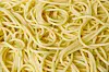 Tett nærbilde av kokt spaghetti som danner et abstrakt mønster.