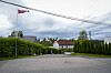 Stille gate i boligområde i Oslo med norsk vimpel, hus og grønne tujahekker under overskyet himmel.
