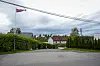 Stille gate i boligområde i Oslo med norsk vimpel, hus og grønne tujahekker under overskyet himmel.