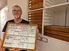 Hallvard Elven viser en innrammet samling med insekter foran hyller med trekasser.