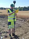 Arkeolog Aksel Haavik står på jordet og skriver i en liten gul bok. Han har på seg refleksvest og gul shorts.