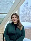 Portrett av Lydia Mathilde Nystad. Hun har på en mørkegrønn skjorte med svart t-skjorte inni. I bakgrunnen skimtes vinduer, ute er det snø.