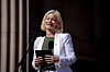 Sigrun Gjerløw Aasland taler på en scene iført hvit jakke og holder et nettbrett.